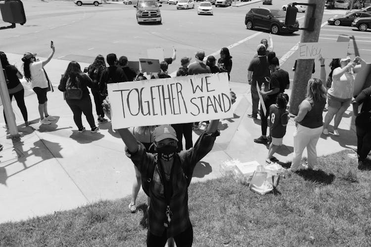 Black And White Photo Of A Street Protest With A Man Holding A Sign