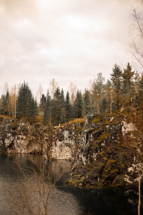 Free Tranquil autumn scene featuring cliffs and a river surrounded by a coniferous forest. Stock Photo