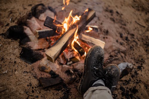 Free Burning Campfire and Feet of a Person in Hiking Boots Stock Photo