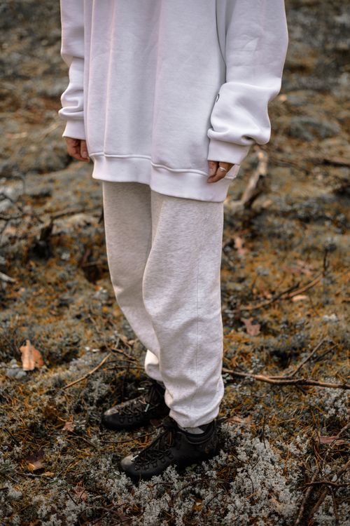 Free Person in white attire stands on earthy ground, showcasing relaxed fashion. Stock Photo