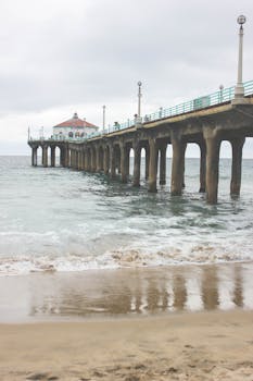 A tranquil view of an iconic pier extending into the sea, under an overcast sky.