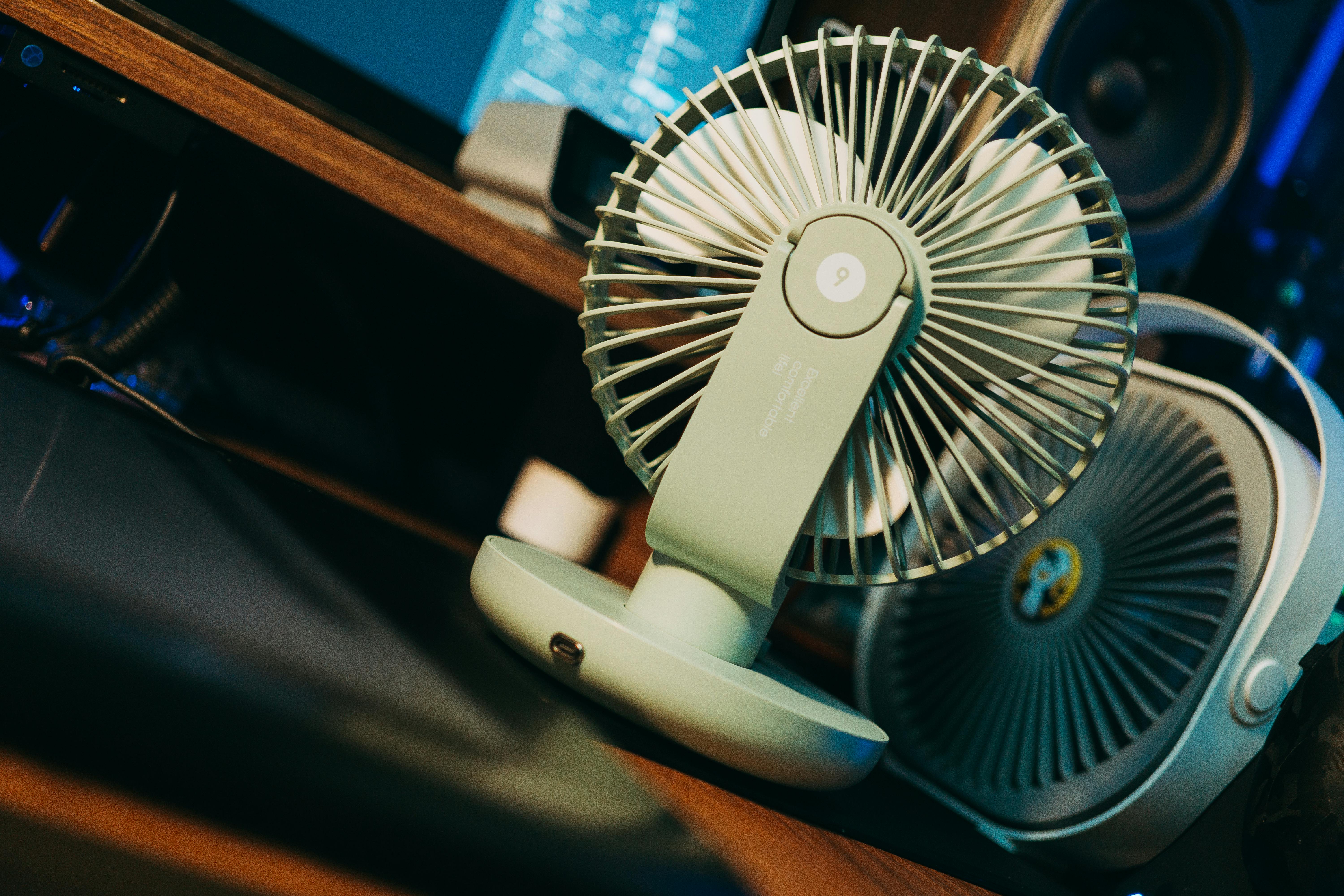 Photo of a desk setup featuring a modern compact fan, emphasizing technology and comfort.