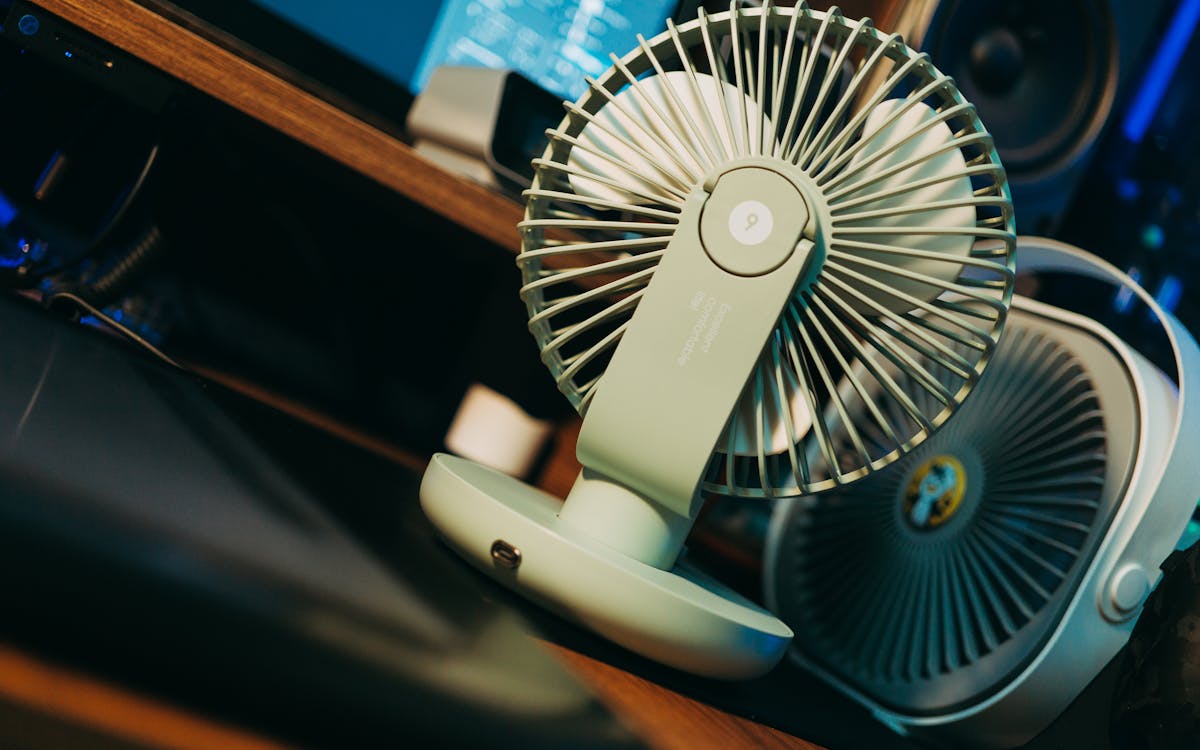 Photo of a desk setup featuring a modern compact fan, emphasizing technology and comfort.
