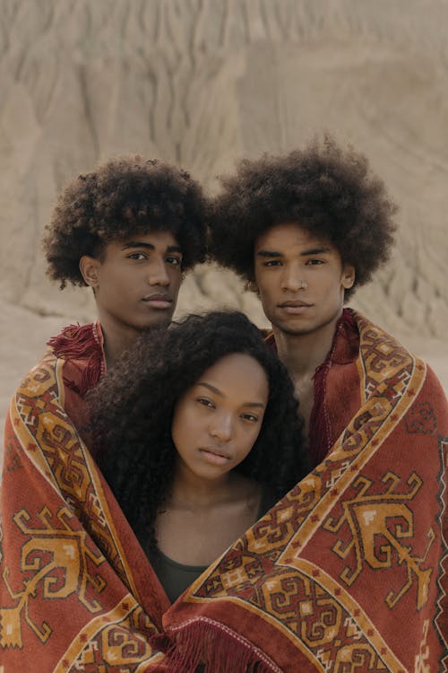 A Woman and Two Men Wrapped in a Blanket