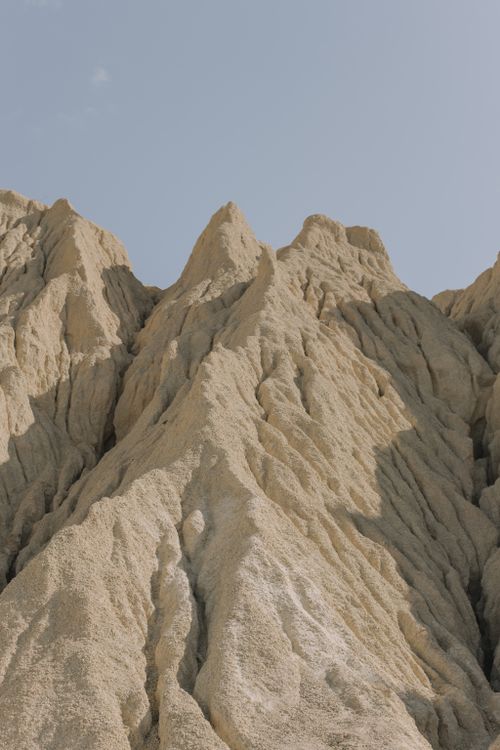 Free Dramatic sandstone peaks rise against a clear blue sky in a desert landscape, captured in summer sunlight. Stock Photo