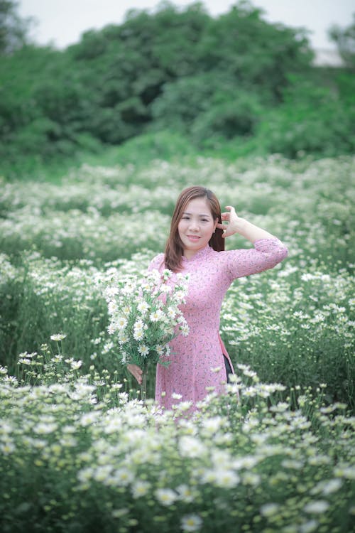 Woman in Pink Floral Dress Standing on Green Grass Field