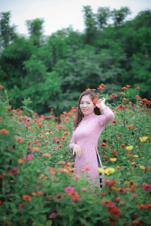 Woman in Pink Long Sleeve Dress Standing on Flower Field