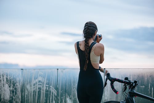 Ciclista Mujer Sin Rostro Bebiendo Cerca De La Bicicleta Bajo El Cielo Nublado