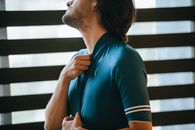 Crop unshaven male athlete putting on sportswear in house