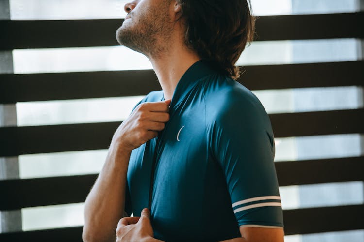 Crop Unshaven Male Athlete Putting On Sportswear In House