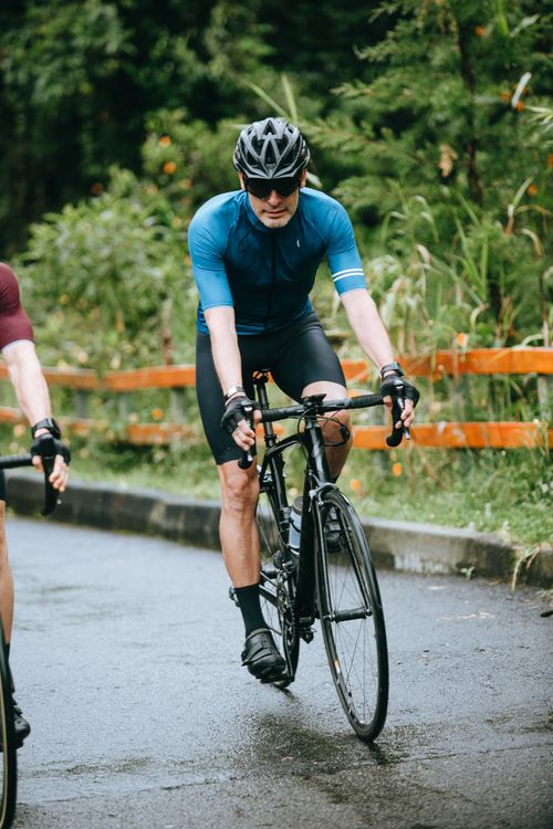 Free Bearded bicyclist in active wear near crop anonymous partner riding bicycles on countryside roadway Stock Photo