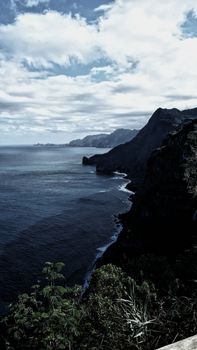 A stunning view of rugged cliffs and ocean waves under a cloudy sky, captured in a serene natural setting.
