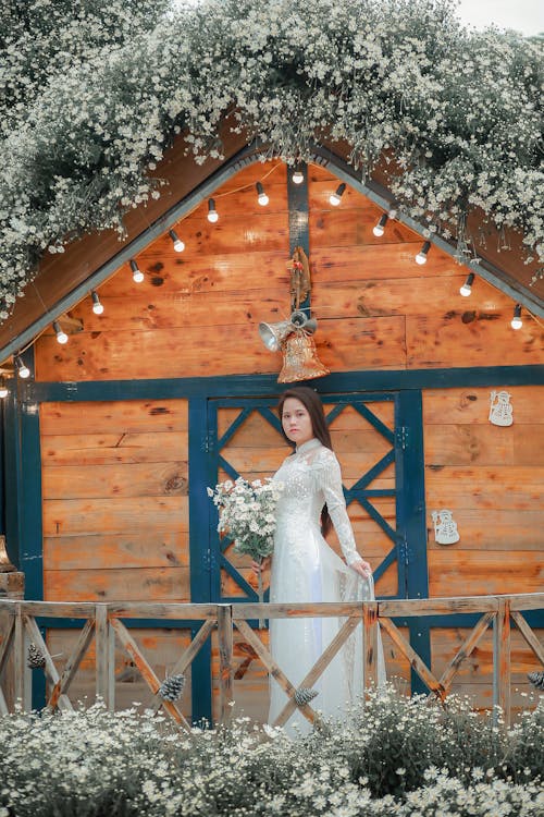 Free Woman in White Wedding Gown Standing Beside Brown Wooden Door Stock Photo
