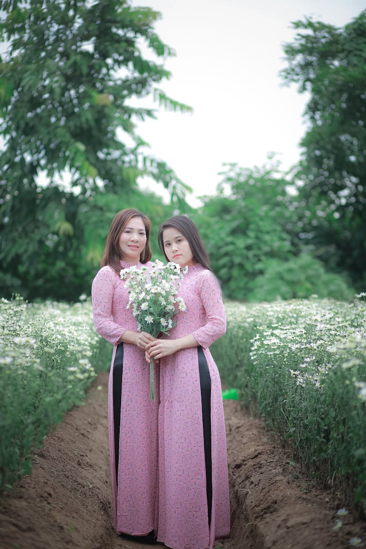 Women In Matching Dresses Standing In Field Of Flo