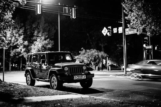 Black and white of contemporary automobile near crossroad with signposts in late evening