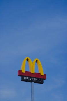 From below of colorful logo signage of modern fast food restaurant with inscription against blue cloudless sky