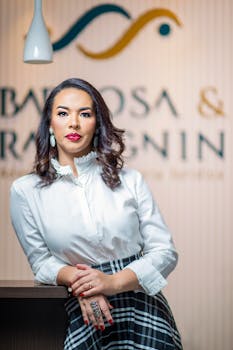 A professional woman in smart casual attire poses confidently indoors.