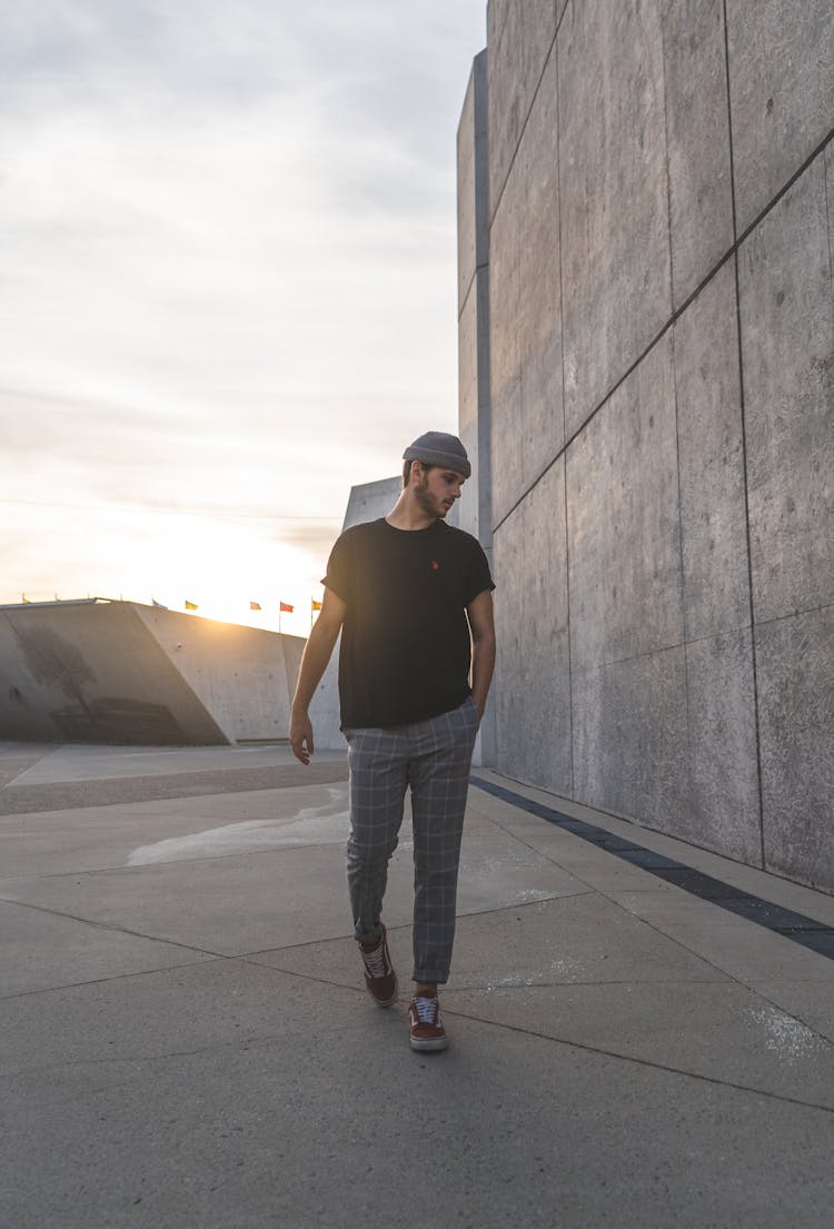 Man Walking Near Concrete Building In Bright Sunlight