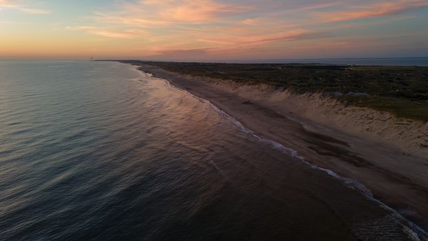 Beautiful aerial view of a sunset over a tranquil Danish coastline, capturing the serene landscape and horizon.