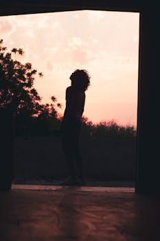 A striking silhouette of a woman with curly hair against a vibrant sunset sky in Mexico.