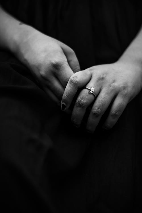 Black and white of crop faceless female with delicate ring on finger in dress