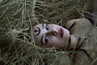 一位女性躺在草丛中，面部设计独特，肖像十分迷人