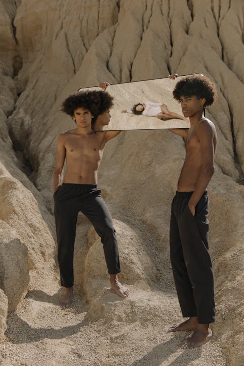 Free Topless Man in Black Pants Standing Beside Brown Rock Stock Photo