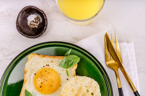 Free Enjoy a tasty breakfast with sunny side up egg on toast, juice, and cutlery. Stock Photo