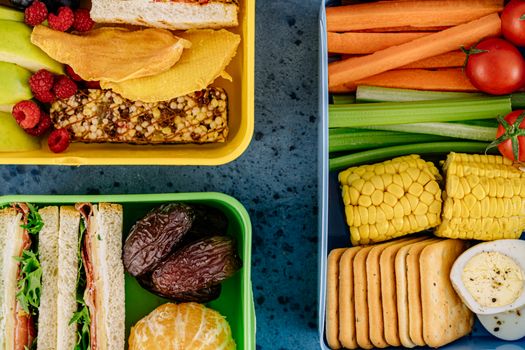 Vibrant lunchboxes packed with healthy snacks, fruits, and sandwiches presented in top view.