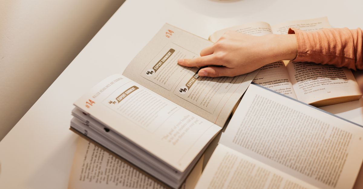 Woman's hand pointing to text in open books, symbolizing study and learning.