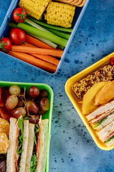A vibrant flat lay of healthy lunch boxes featuring sandwiches, fruits, and vegetables, perfect for a nutritious meal.