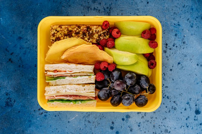 divided bento box with cheese, crackers, fruit, and nuts