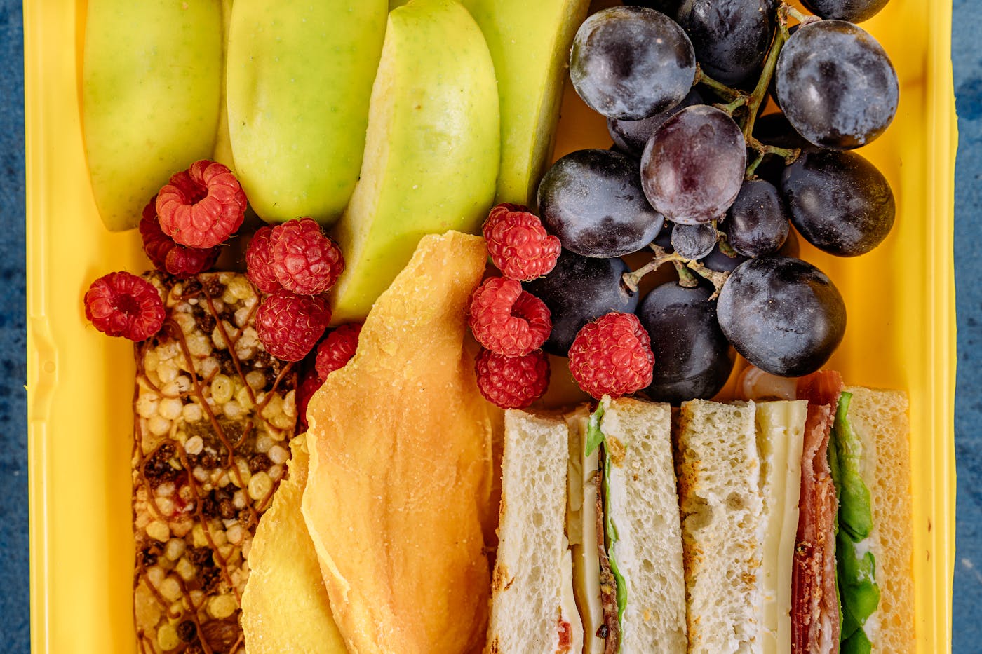 Scatto dall'alto di lunchbox con panini frutta e snack assortiti