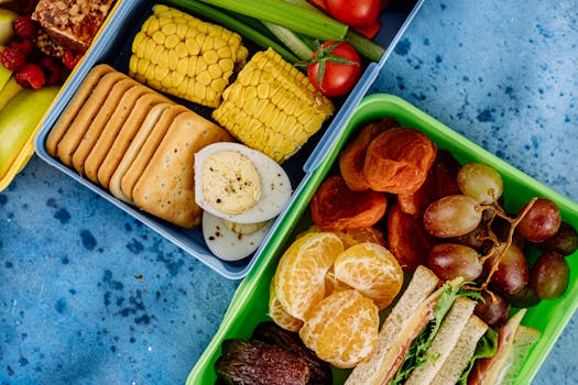 Colorful lunchboxes with fruits, snacks, and vegetables for a balanced meal.