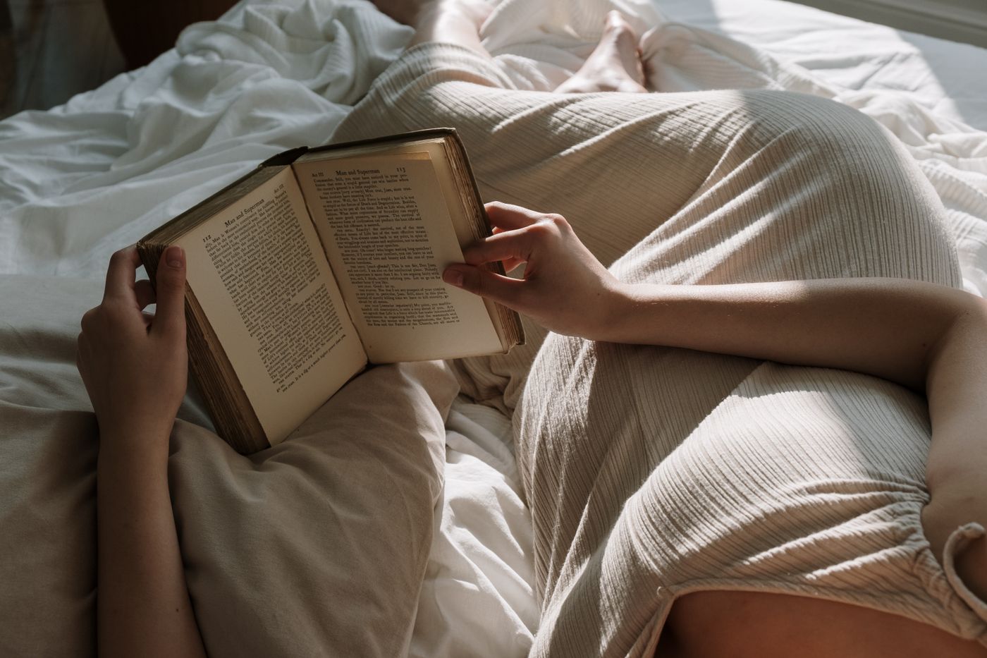Future maman lisant paisiblement dans son lit dans une chambre lumineuse