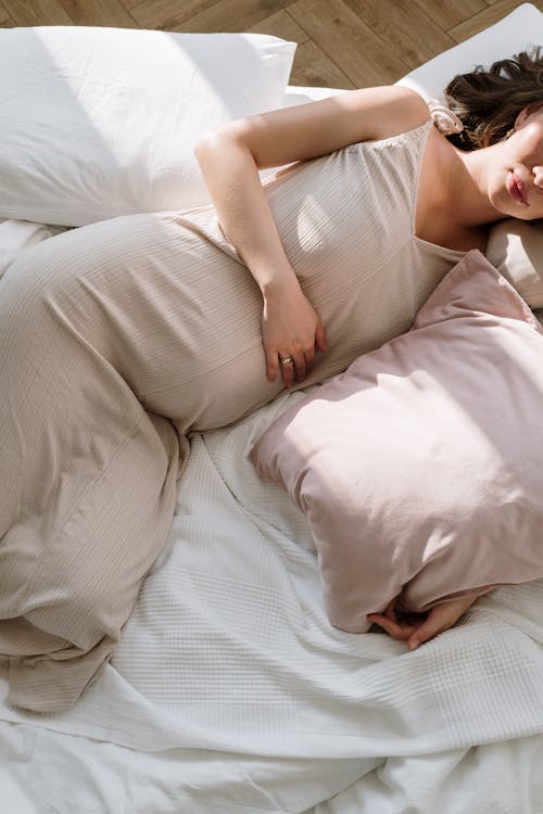 Free A Pregnant Woman Lying on Bed Stock Photo