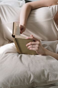 女人躺在床上，枕着枕头，安静地读着一本精装书