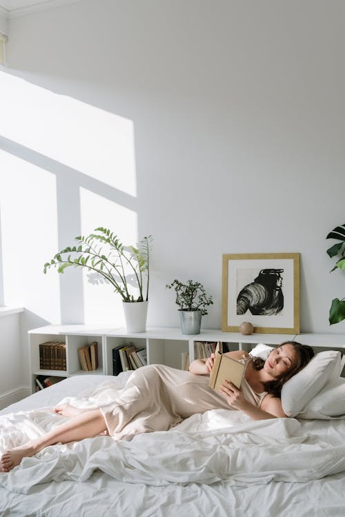 Free A Woman Lying on Bed Reading Book Stock Photo