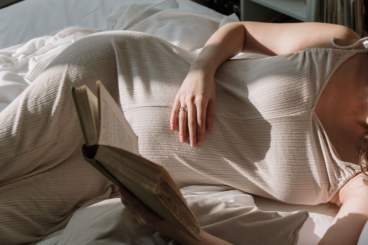 Future maman lisant un livre dans son lit pendant un moment calme
