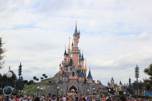 Scenic view of Sleeping Beauty Castle at Disneyland Paris with a bustling crowd.