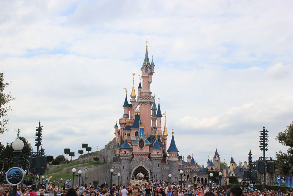 Scenic view of Sleeping Beauty Castle at Disneyland Paris with a bustling crowd.