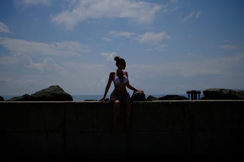 A Woman in a Bikini Sitting on a Ledge Wall