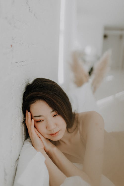A Woman Leaning on the White Wall while Posing