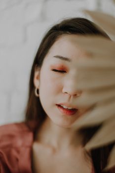 Artistic portrait of a woman with eyes closed, partially covered by soft focus object.