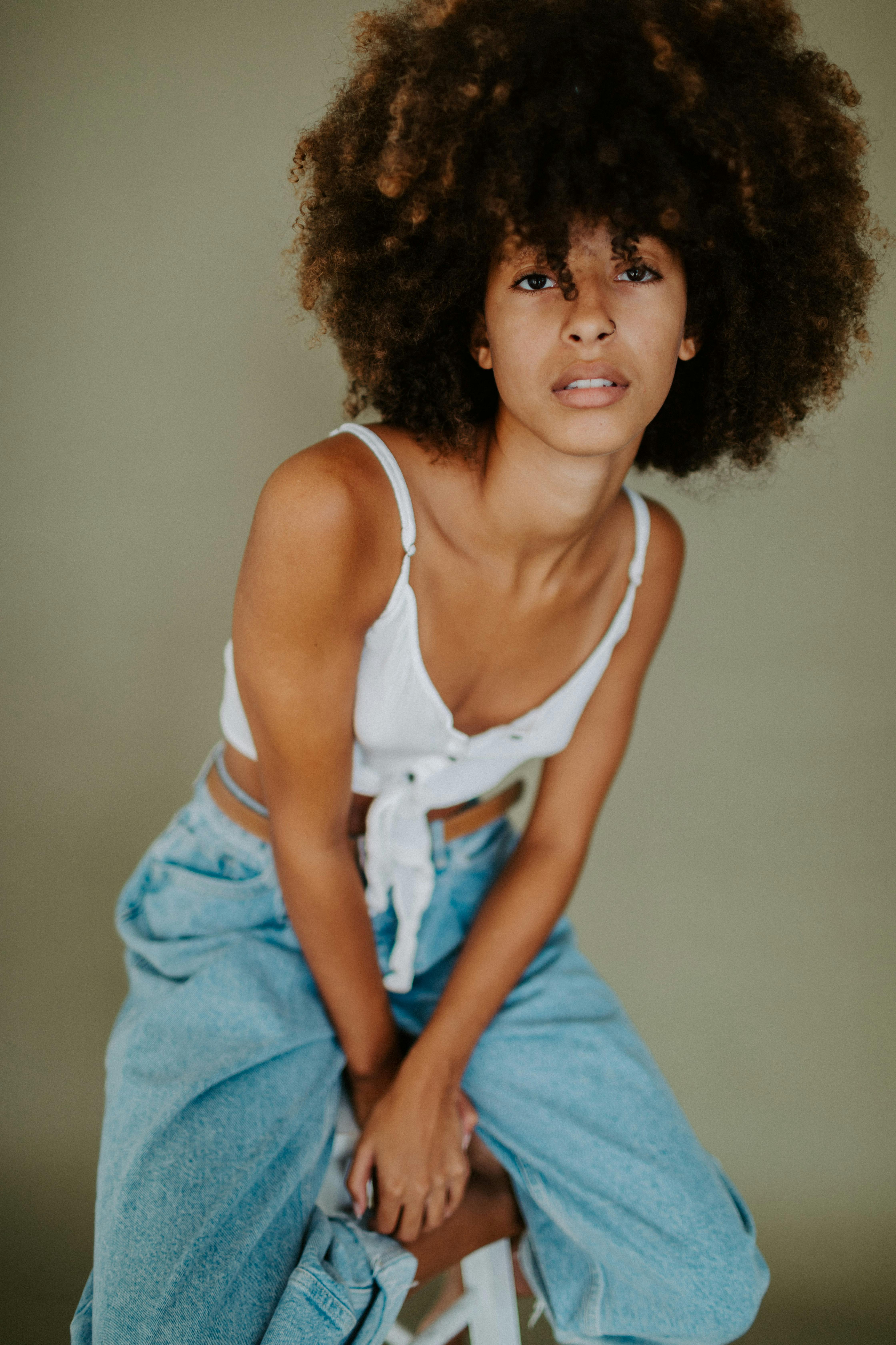 Elegant studio portrait of a woman with afro hair, wearing casual attire.