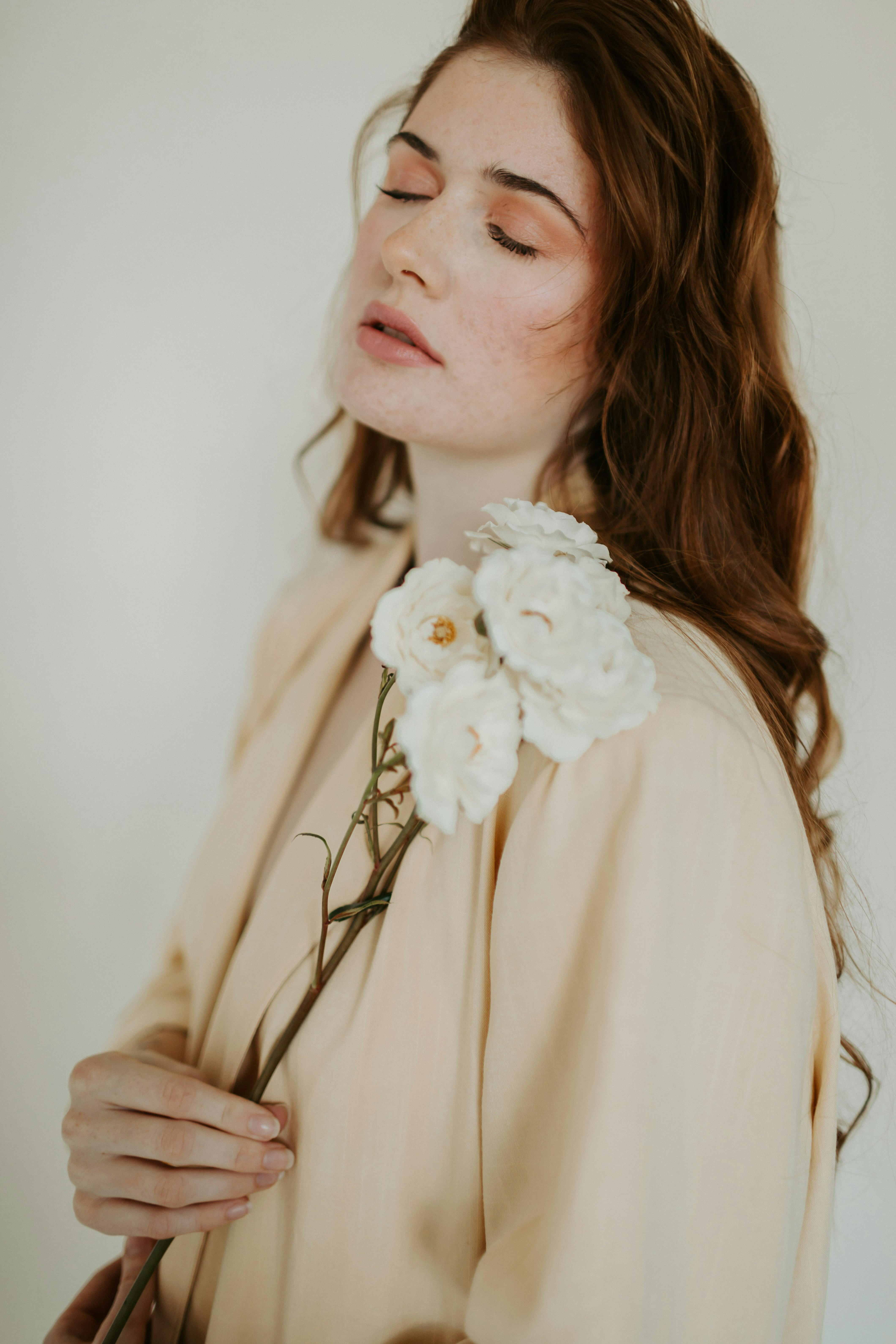 Beautiful portrait of a woman holding white flowers with eyes closed, exuding peace.