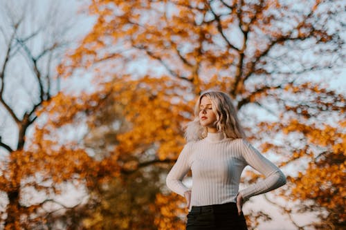 Woman in White Knitted Sweater Standing Near a Tree