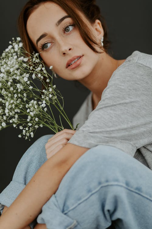 Woman in Gray Sleeve Shirt Sitting Holding a Bouquet of Flowers