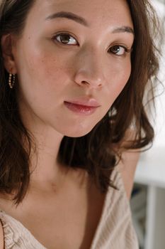 Elegant close-up of an adult woman with natural beauty in a relaxed indoor setting.