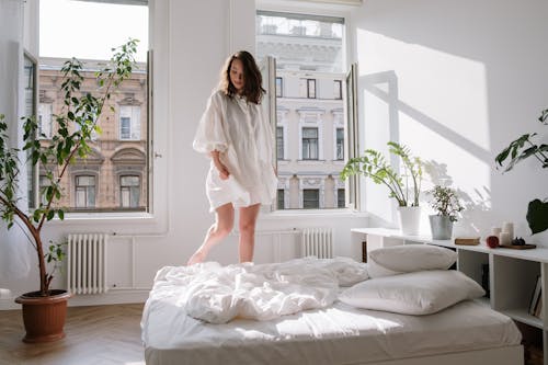 Woman in White Dress Standing on the Bed